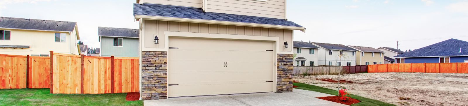 Two-story blue suburban house with a white triple garage door and well-maintained front yard in Mahtomedi