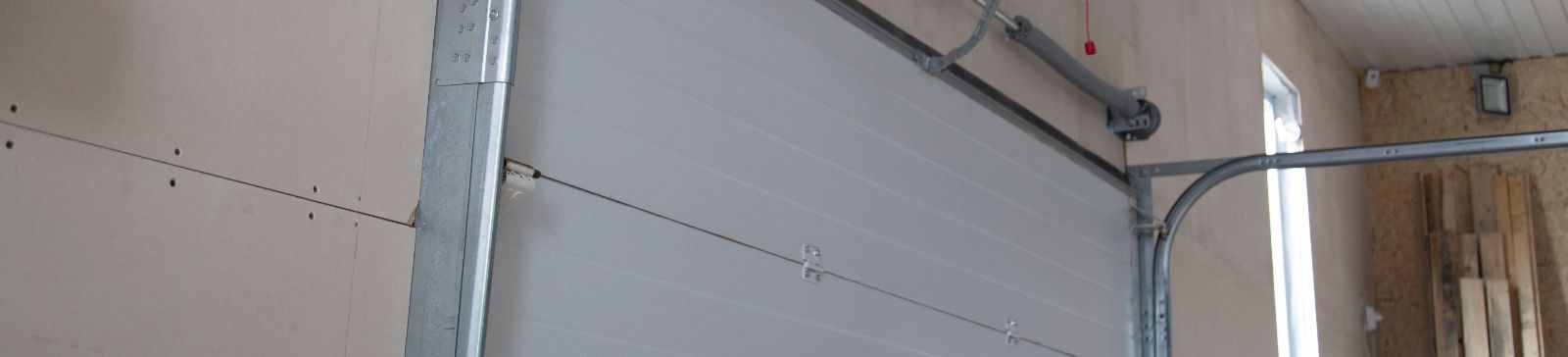 Interior view of a newly installed sectional overhead garage door with steel tracks and torsion spring system in a Mahtomedi residential garage.