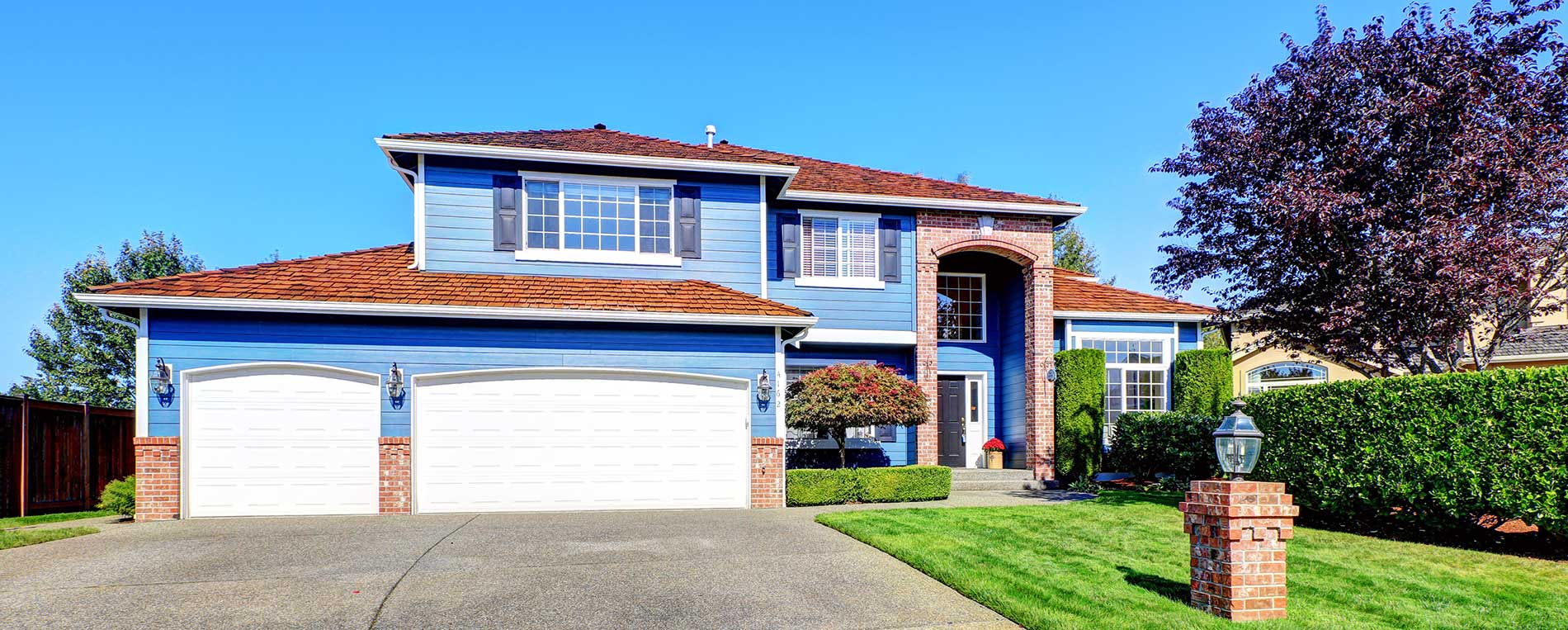 Residential home in Mahtomedi with repaired white garage doors and red brick trim