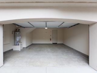 Clean and Well-Maintained Overhead Garage Door – Maintenance Tips Spacious, clean two-car garage with an open overhead door, showing a well-maintained floor and organized utility area.